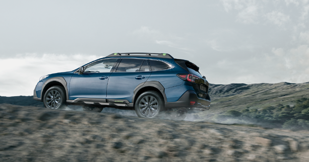 Modelo Subaru en terreno montañoso con cielo nublado de fondo