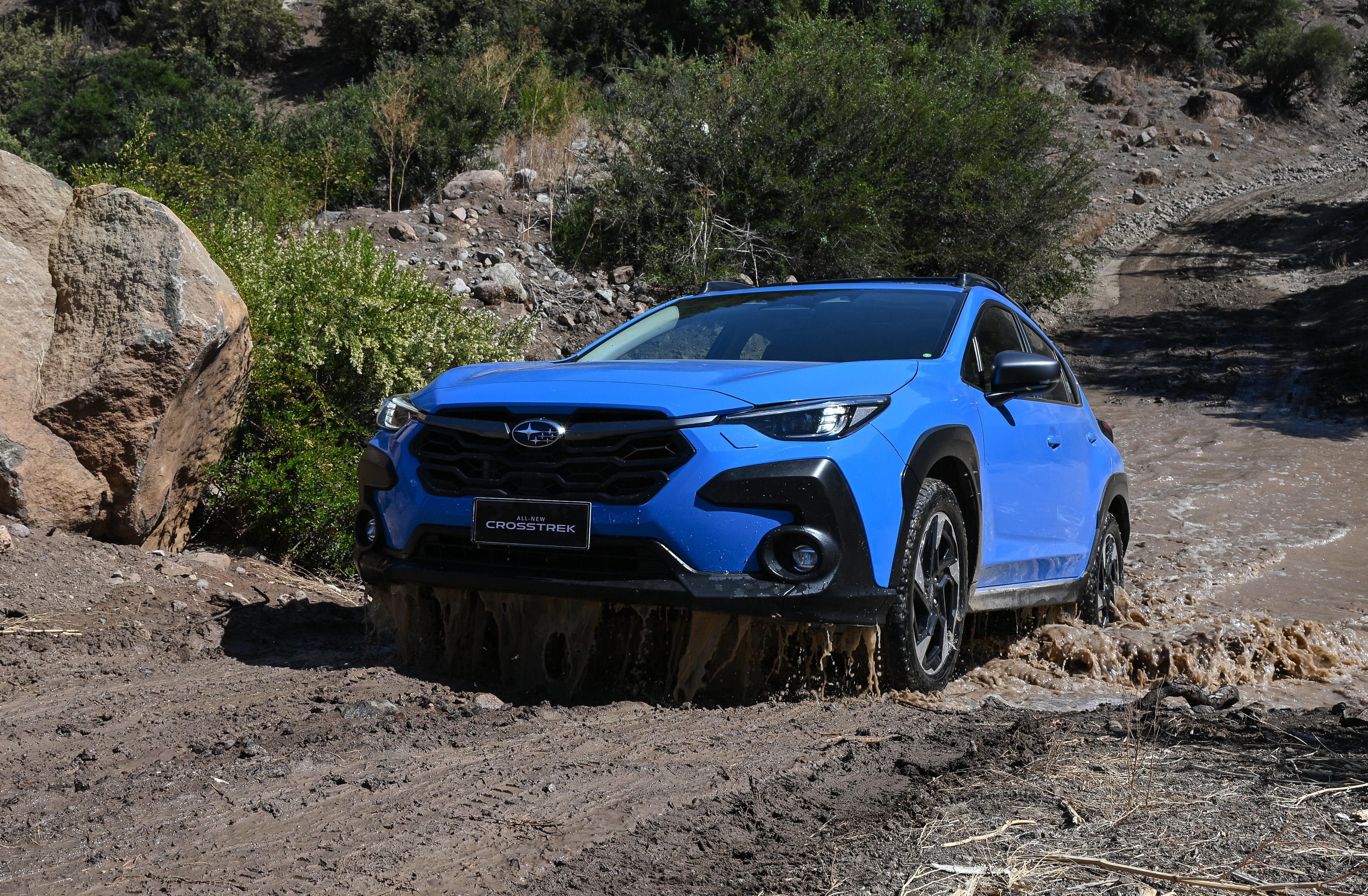 Subaru Crosstrek color azul en terreno con lodo y vegetación de fondo
