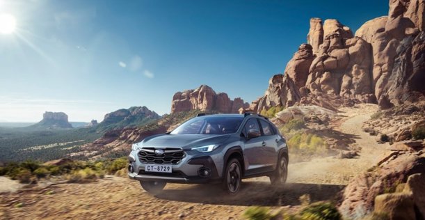 Subaru Crosstrek sobre terreno arenoso y montañas de fondo