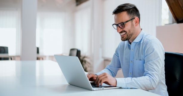 hombre sonriente frente a computador sentado en oficina