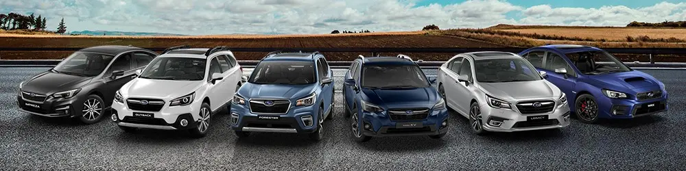 Modelos Subaru estacionados uno al lado de otro con vegetación de fondo