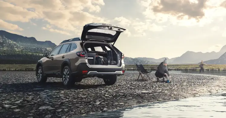 Auto Subaru estacionado en frente de lago con montaña de fondo