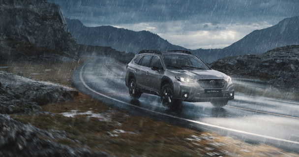 Subaru Outback color plateado en carretera bajo la lluvia