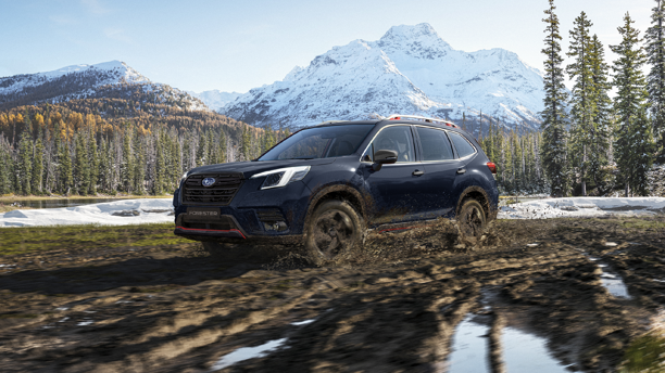 Subaru Forester con tracción 4x4 en terreno de lodo con nevado de fondo