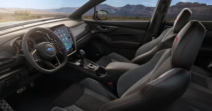 Interior de auto WRX mostrando asientos delanteros, volante y pantalla inteligente