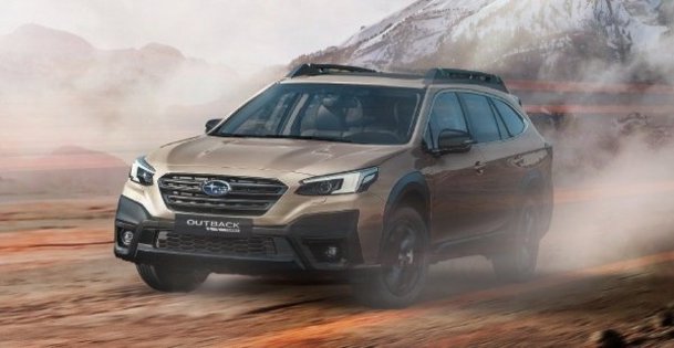 Subaru Outback sobre terreno arenoso con montañas de fondo
