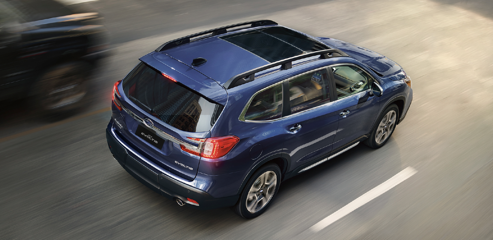 Vista desde arriba de SUV 7 pasajeros Evoltis color azul oscuro, a velocidad en calle de ciudad