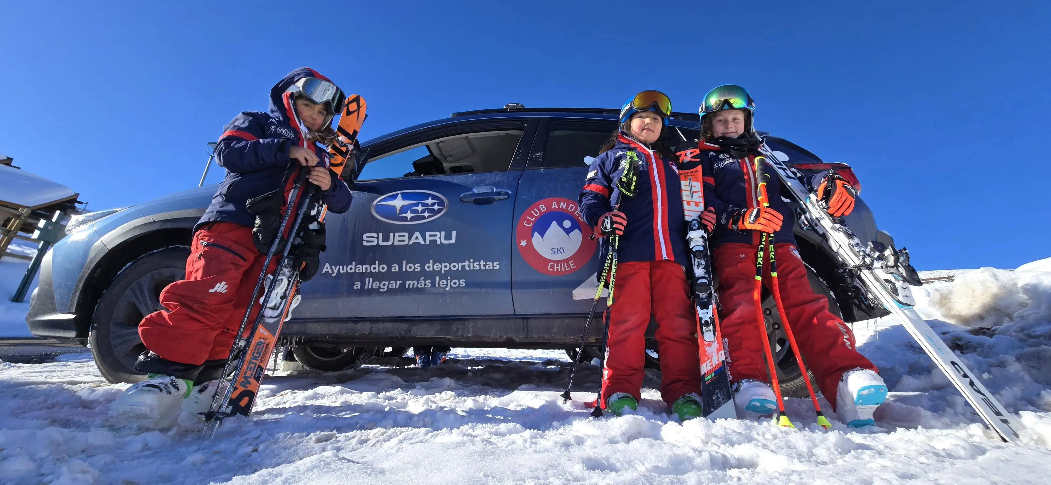 niños deportistas con indumentaria de esquí con auto Subaru en nieve