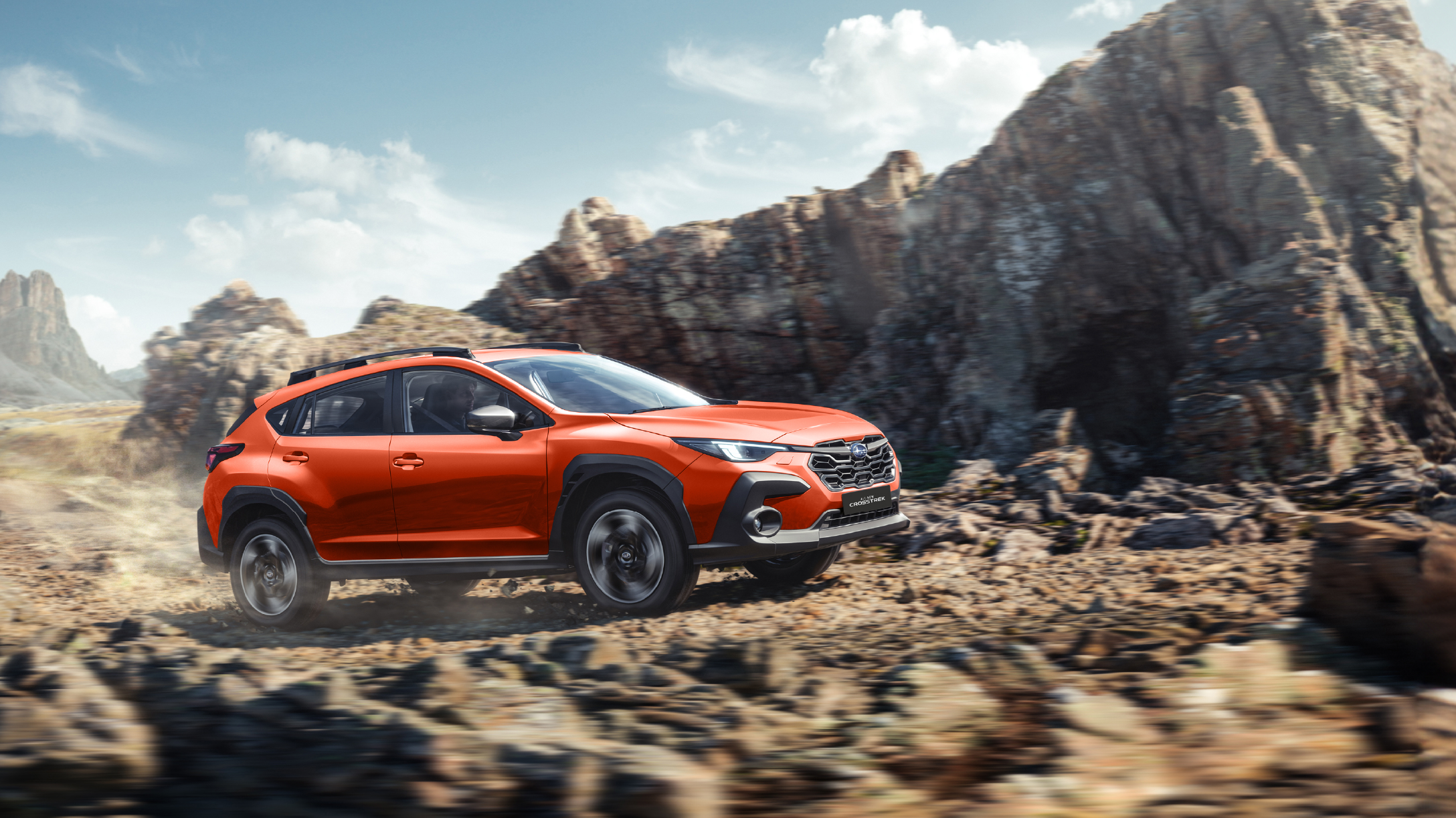 Subaru Crosstrek en terreno rocoso con montañas de fondo